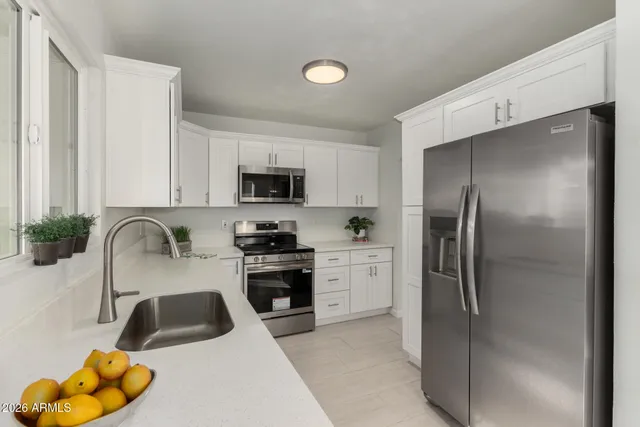 a kitchen with a refrigerator sink and white cabinets