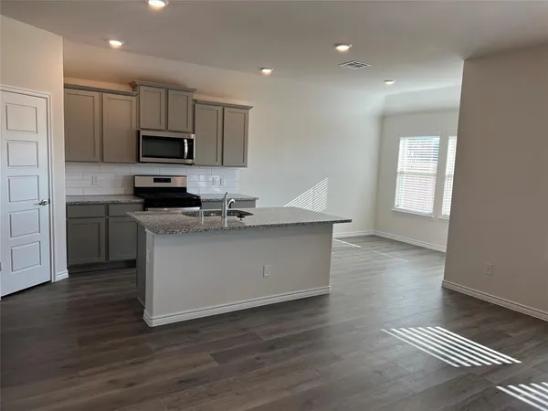 a kitchen with stainless steel appliances granite countertop a sink a stove a microwave a sink a refrigerator and cabinets