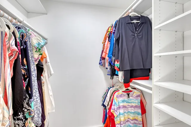 a view of walk in closet with clothes and shoes