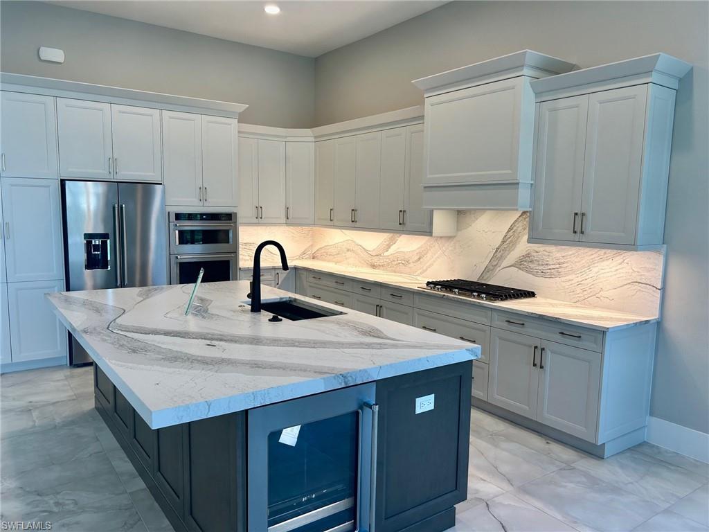 9475 Caymas Way Naples, FL 34114 - Photo 3 of 8 a kitchen with stainless steel appliances granite countertop a sink dishwasher and stove