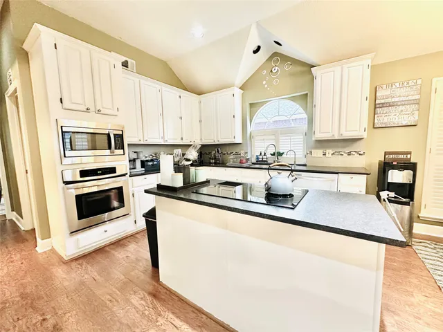 a kitchen with stainless steel appliances granite countertop a sink and white cabinets