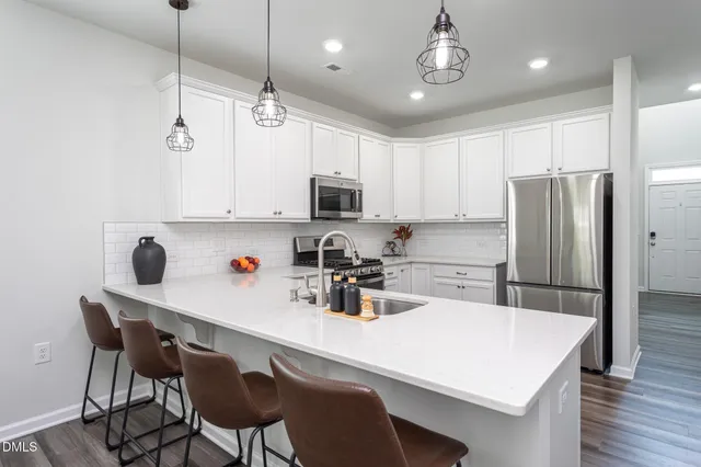 a kitchen with stainless steel appliances kitchen island granite countertop a dining table chairs and sink