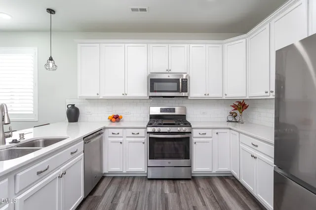 a kitchen with white cabinets stainless steel appliances and sink
