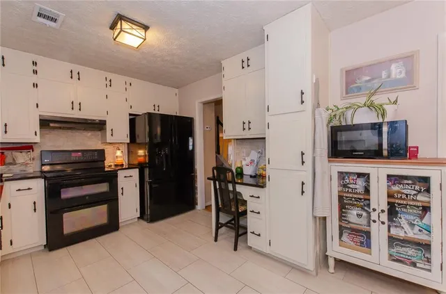 a kitchen with stainless steel appliances kitchen island granite countertop a table chairs in it and white cabinets