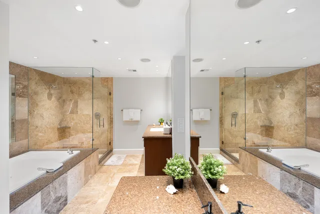 a spacious bathroom with a granite countertop tub shower and mirror