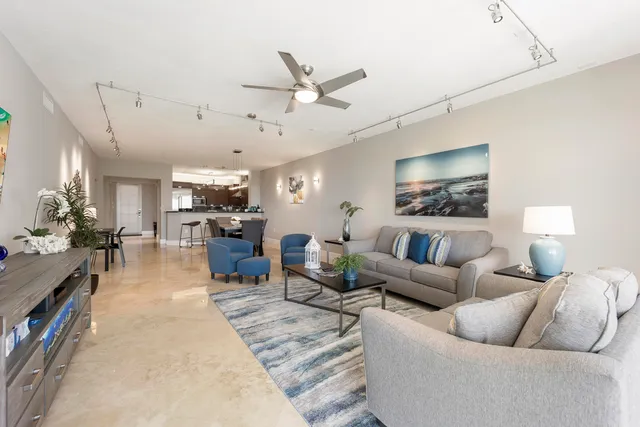 a living room with furniture kitchen view and a wooden floor