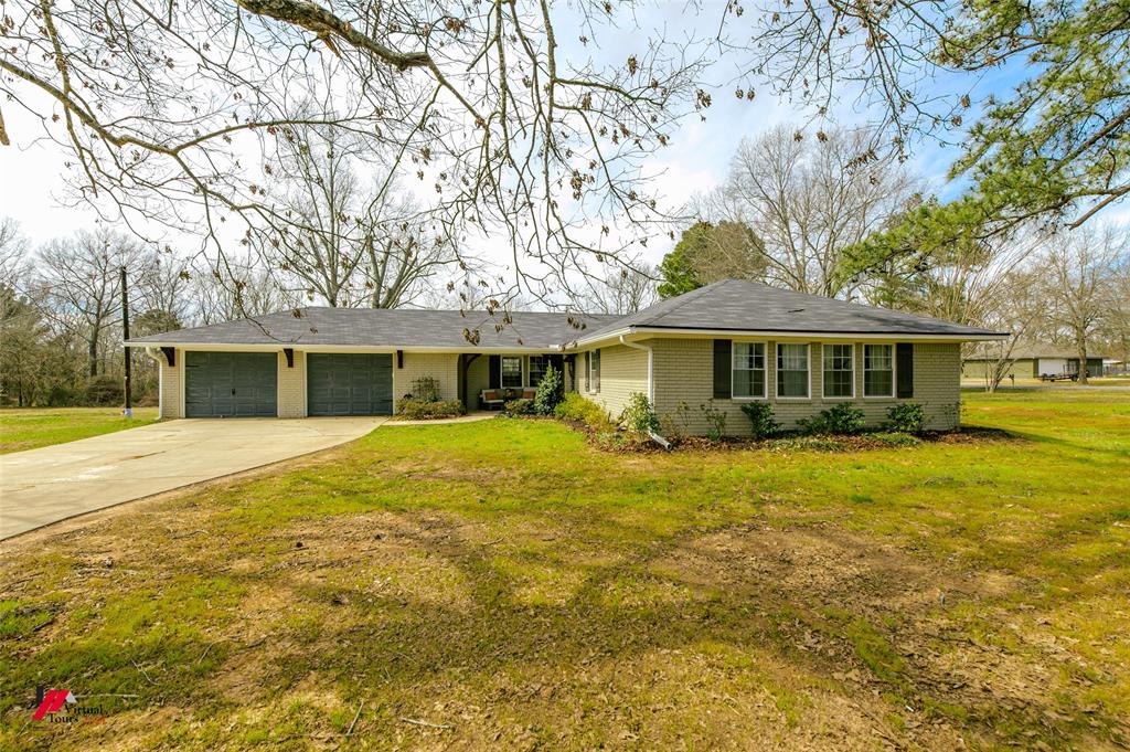 Ranch-style house featuring a garage, a front yard, concrete driveway, and brick siding