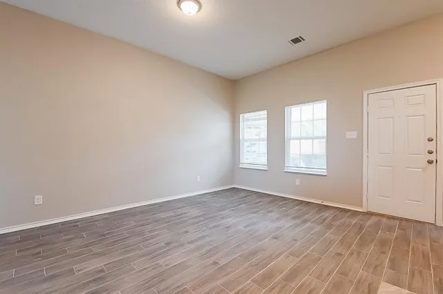 an empty room with wooden floor and windows