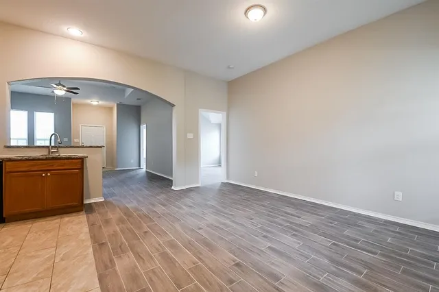 an empty room with wooden floor and a kitchen