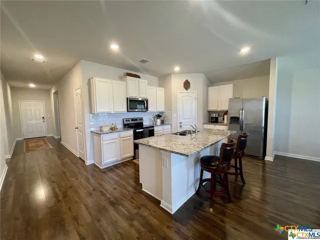 a kitchen with kitchen island granite countertop a sink cabinets and wooden floor