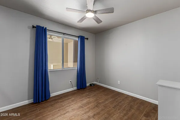 a view of empty room with wooden floor and fan