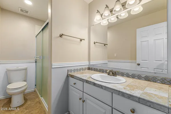 a bathroom with a granite countertop sink a toilet and a mirror