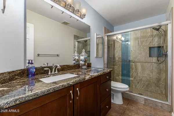 a bathroom with a granite countertop sink a toilet and shower