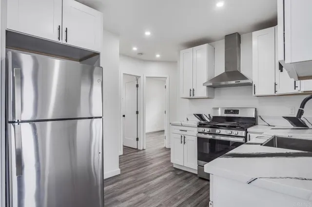 a kitchen with stainless steel appliances a refrigerator a stove and white cabinets