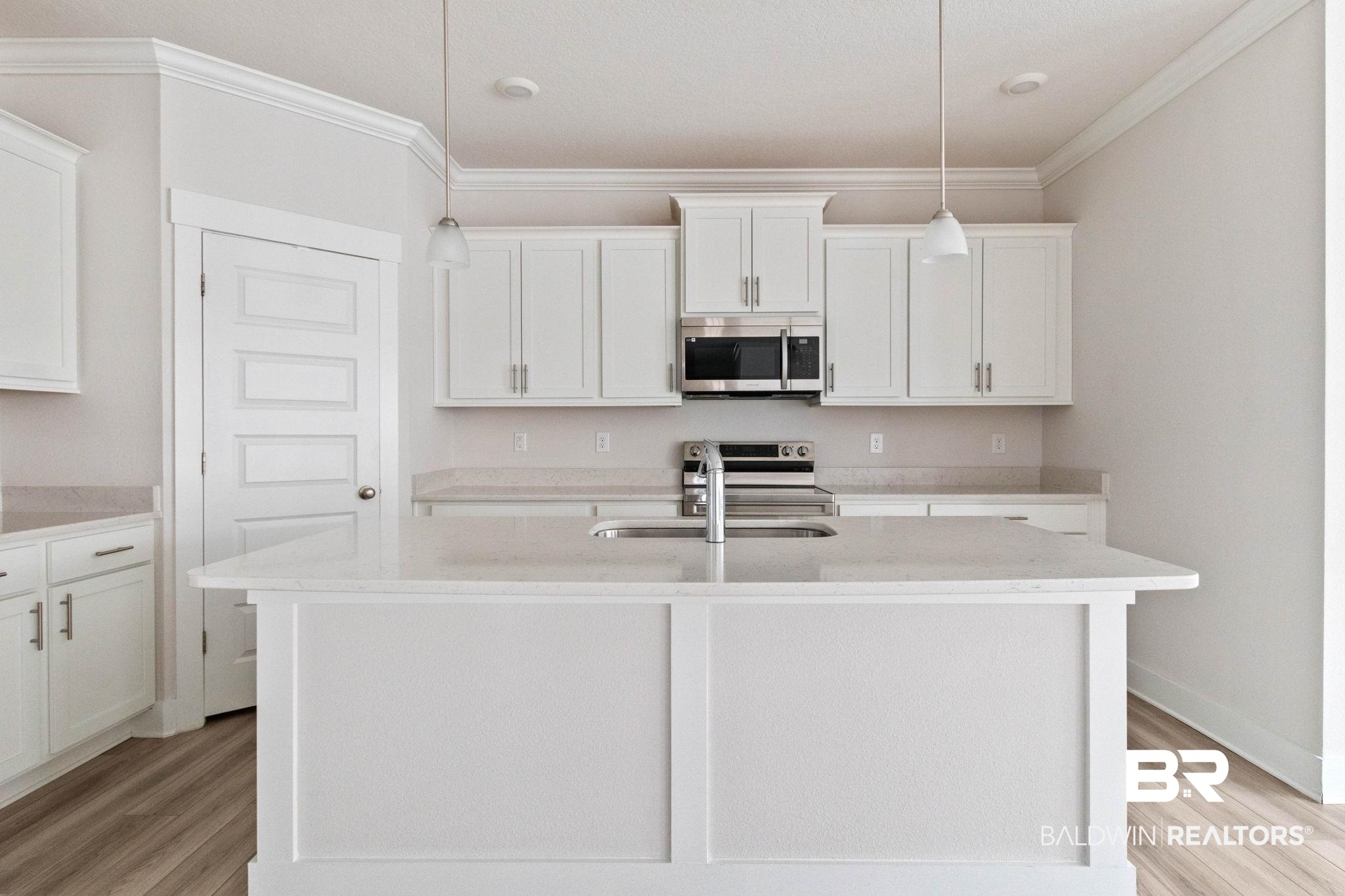 1710 Grouse Street Foley, AL 36535 - Photo 24 of 76 Kitchen featuring a central island with an undermount sink, white cabinetry, integrated stainless steel appliances, light-toned countertops, and wood-finish flooring