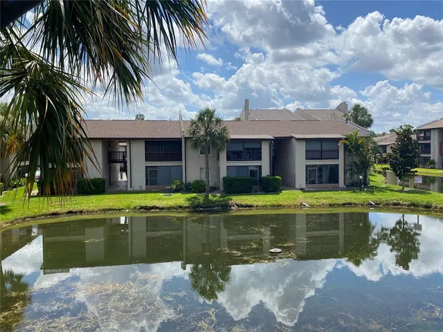a view of a swimming pool with a yard and palm trees