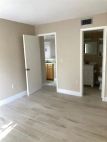 a view of an empty room with wooden floor and closet
