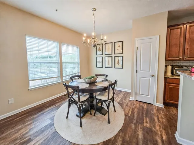 a dining room with wooden floor a chandelier a wooden table and chairs
