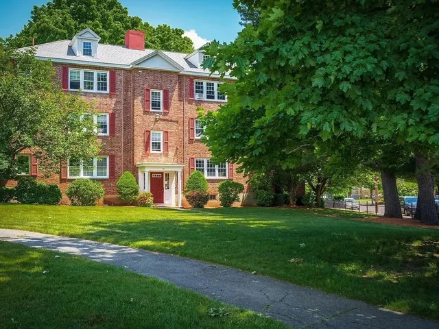 a view of a big house with a big yard and large trees