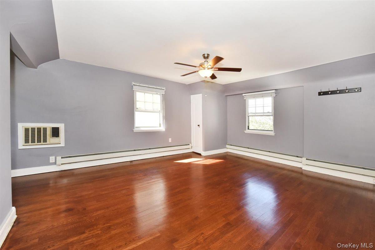 139-30 Coolidge Avenue Queens, NY 11435 - Photo 12 of 34 Empty room with dark wood-style flooring, plenty of natural light, and a baseboard radiator