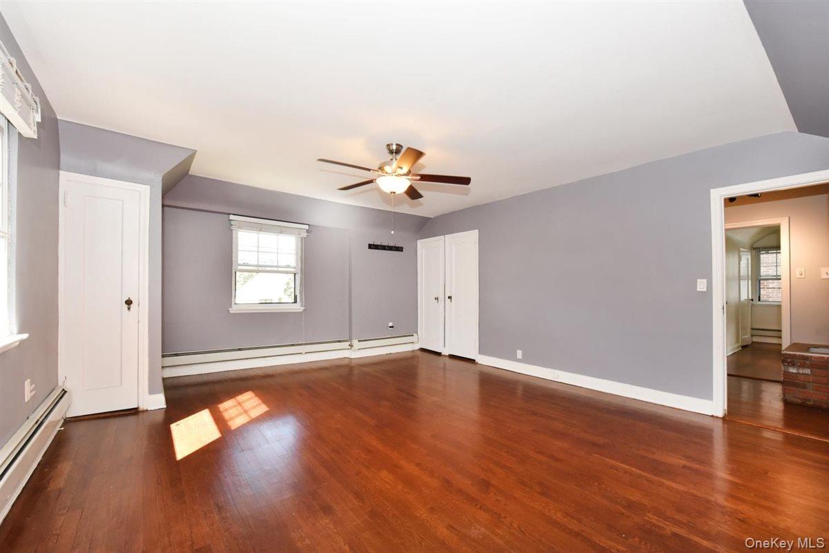 139-30 Coolidge Avenue Queens, NY 11435 - Photo 13 of 34 Unfurnished bedroom featuring dark wood finished floors, a baseboard heating unit, and a ceiling fan
