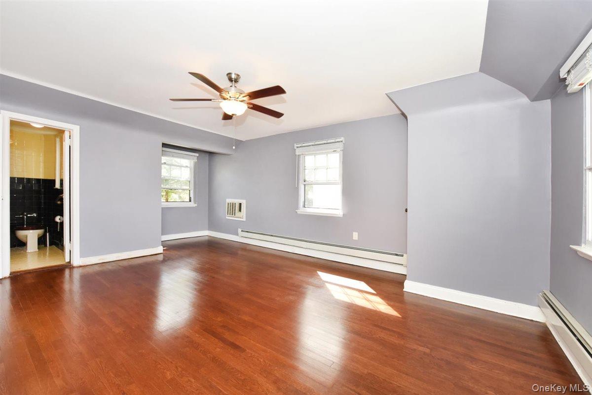 139-30 Coolidge Avenue Queens, NY 11435 - Photo 14 of 34 Unfurnished living room featuring a baseboard heating unit, dark wood-type flooring, a baseboard radiator, and a ceiling fan