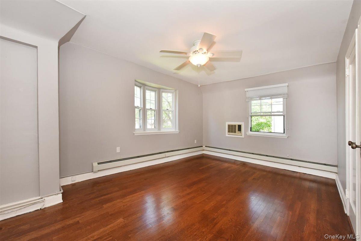 139-30 Coolidge Avenue Queens, NY 11435 - Photo 15 of 34 Empty room featuring dark wood-type flooring, a baseboard heating unit, and a ceiling fan