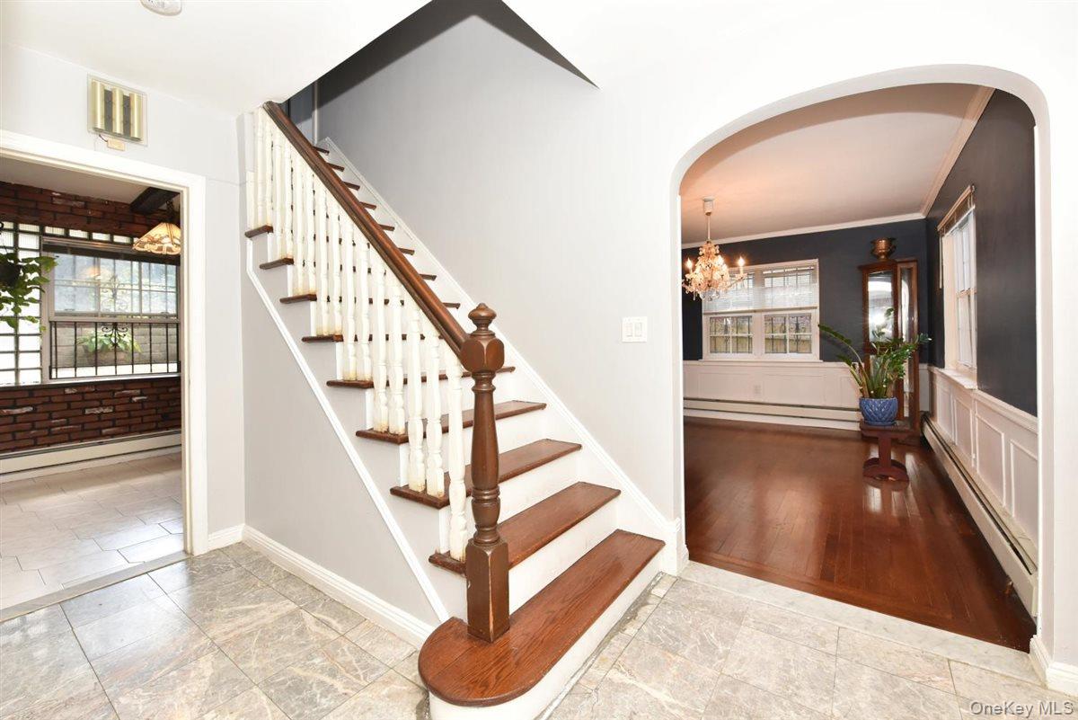 139-30 Coolidge Avenue Queens, NY 11435 - Photo 3 of 34 Stairs with baseboard heating, arched walkways, a baseboard heating unit, crown molding, and a chandelier