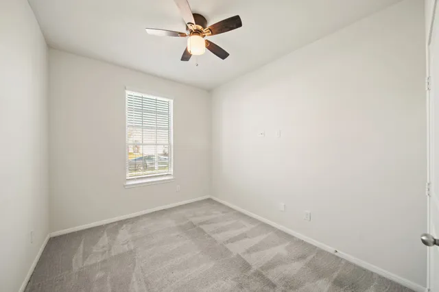 an empty room with a window and a fan