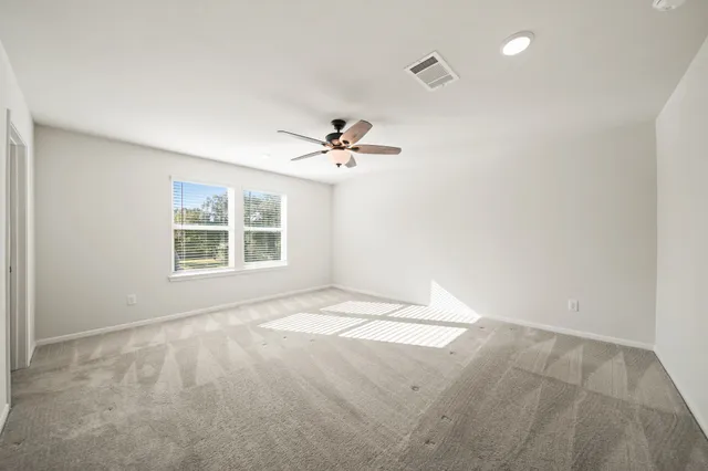 an empty room with windows and ceiling fan view