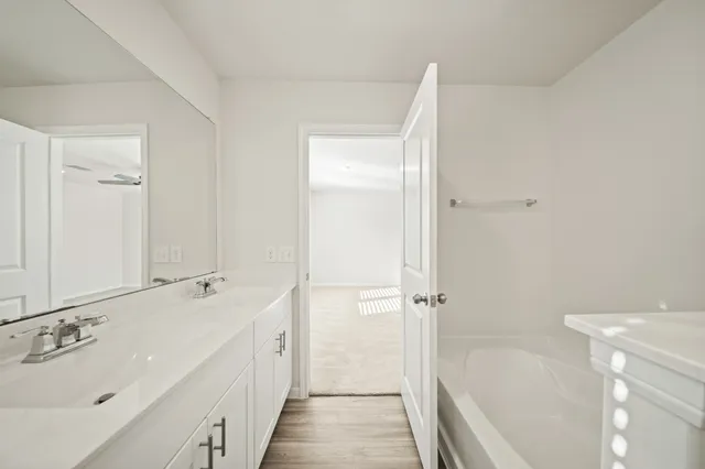 a spacious bathroom with a tub sink and mirror