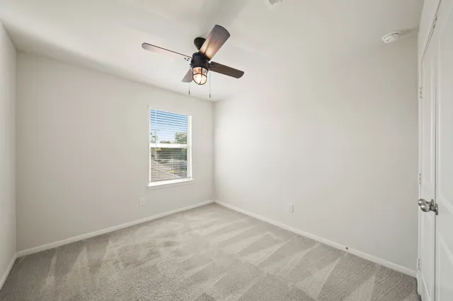 a view of empty room with windows and ceiling fan
