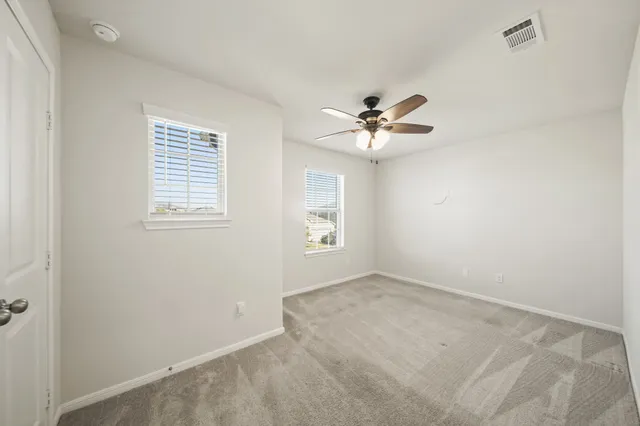 an empty room with windows and fan