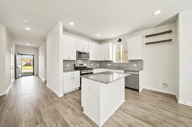 a kitchen with granite countertop white cabinets and white appliances