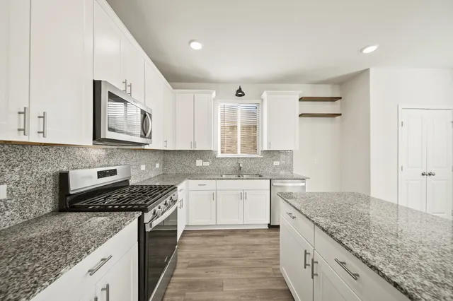 a kitchen with stainless steel appliances granite countertop a sink stove and cabinets