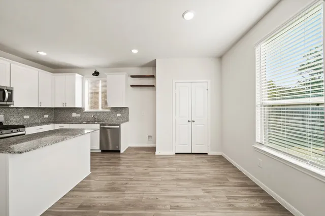 a large kitchen with granite countertop a stove top oven a sink a counter space and cabinets