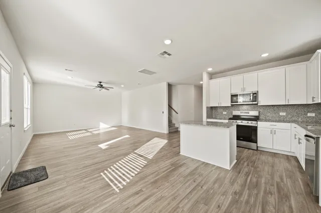 a kitchen with wooden floors white cabinets and stainless steel appliances