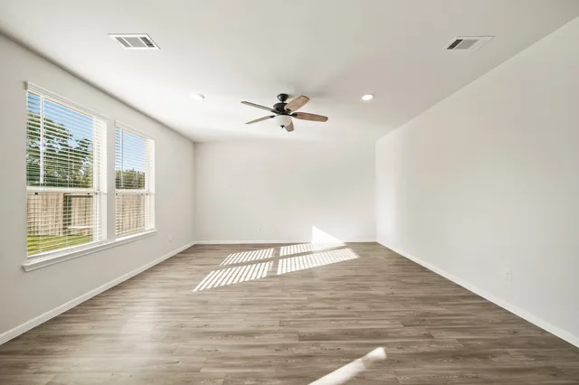 a view of an empty room with a window and wooden floor