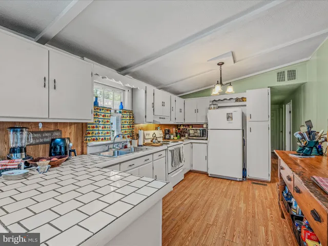 a kitchen with stainless steel appliances a refrigerator and a wooden floor