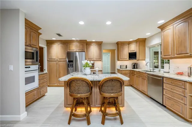 a kitchen with stainless steel appliances granite countertop a table chairs sink refrigerator and cabinets