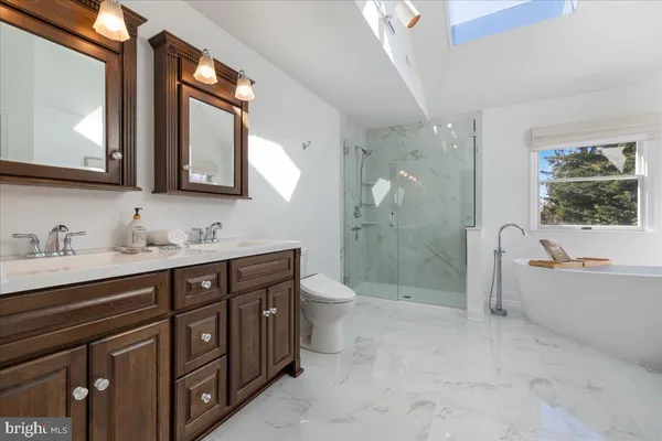 a spacious bathroom with a double vanity sink toilet mirror and bathtub