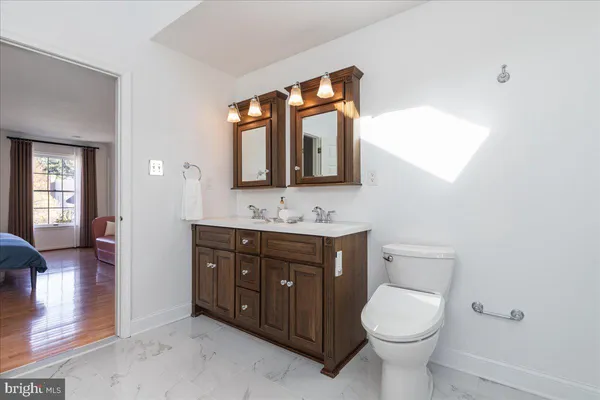 a bathroom with a toilet sink vanity granite and mirror