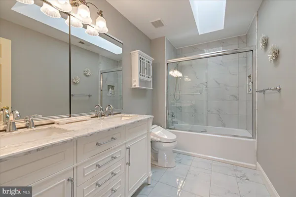 a bathroom with a granite countertop sink toilet mirror and bathtub