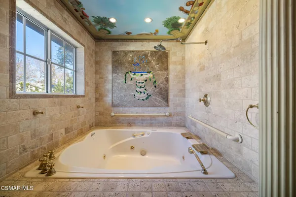 a bathroom with a tub a window and a shower