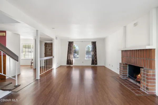a view of an empty room with wooden floor and a fireplace