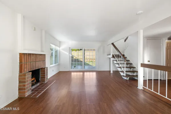 a view of empty room with wooden floor and fireplace