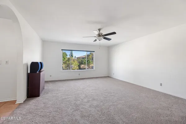 an empty room with windows and with ceiling fan