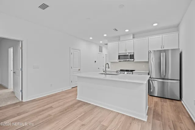 a kitchen with stainless steel appliances granite countertop a refrigerator sink and white cabinets