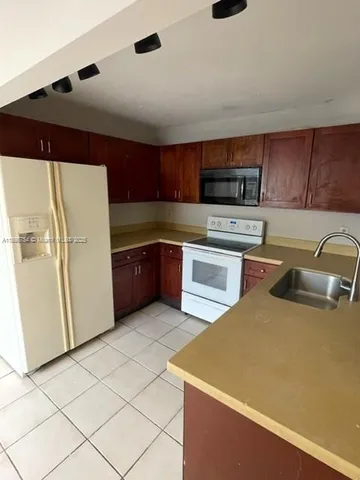 a kitchen with stainless steel appliances granite countertop a refrigerator a stove and a sink with wooden cabinets