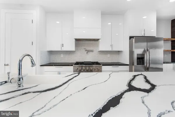 a kitchen with stainless steel appliances kitchen island granite countertop a sink a stove a refrigerator and cabinets